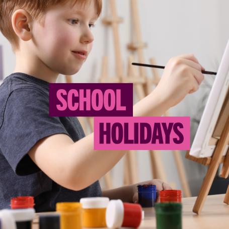 Text 'School Holidays'. With a boy painting a mini canvas on an easel.