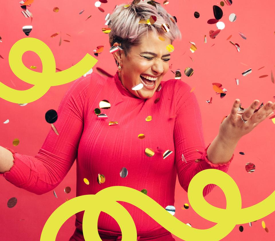 A happy woman with confetti falling on her.
